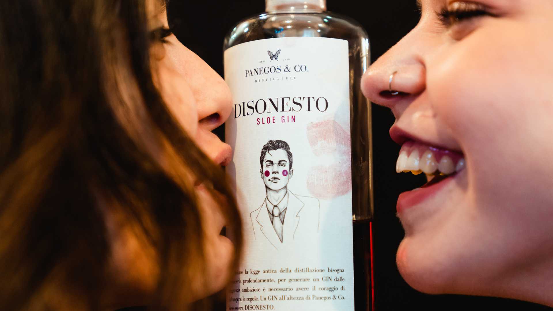 Due persone vicino a una bottiglia di Panegos "Disonesto" Sloe Gin